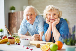 Un uomo e una donna anziani in cucina con frutta sul bancone