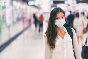 Coronavirus Asian woman walking with surgical mask face protection walking in crowds at airport train station work commute to hospital.