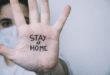 Woman on a side with his hand facing in front with the sentence "stay at home" written on the palm of her hand. Coronavirus concept.