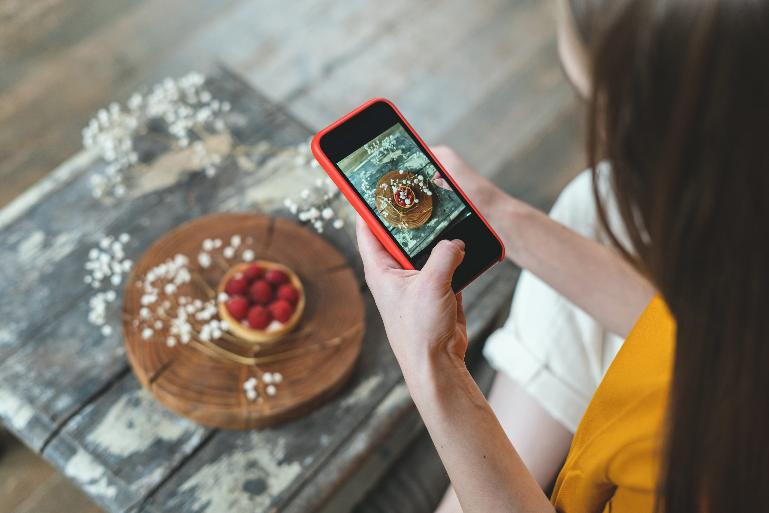 Una giovane donna fotografa un dolce con lo smartphone; concept: food influencer