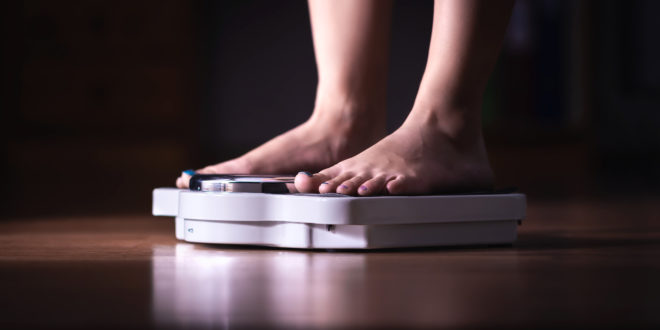 comportamento alimentare, Feet on scale. Weight loss and diet concept. Woman weighing herself. Fitness lady dieting. Weightloss and dietetics. Dark late night mood.