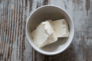 Pezzi di formaggio cremoso in una tazza di ceramica bianca su un tavolo di legno