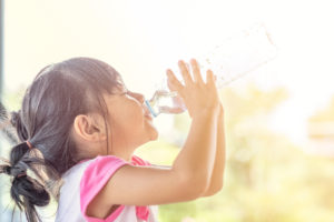 Bambina piccola beve acqua da una bottiglia