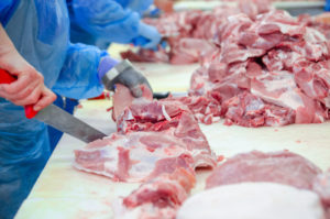 Negozio di disossamento della carne. Macellaio. Macellai tagliano carne di maiale. Linea di produzione di prelibatezze a base di salsiccia.