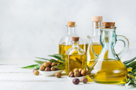 Assortimento di bottiglie di olio extravergine di oliva con olive