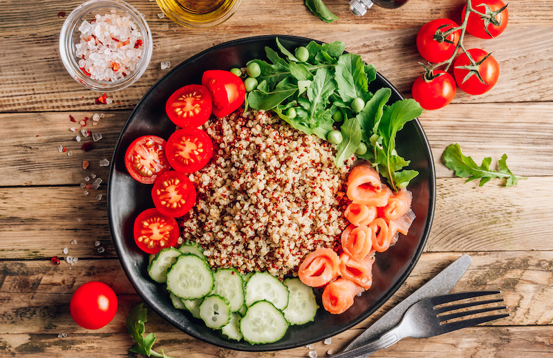 Dish with cereal salad, salmon, cucumbers, cherry tomatoes