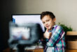 child blogger shoots video on camera, smiling, unpacking blog, video recording at home for blog for followers
