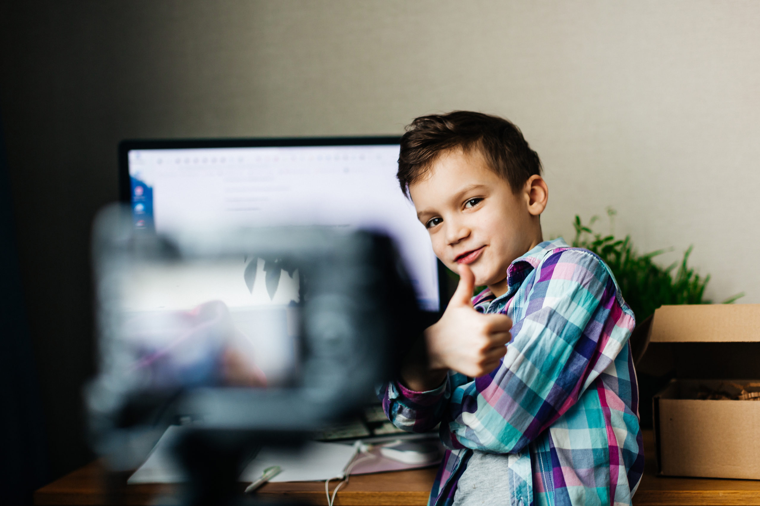 child blogger shoots video on camera, smiling, unpacking blog, video recording at home for blog for followers