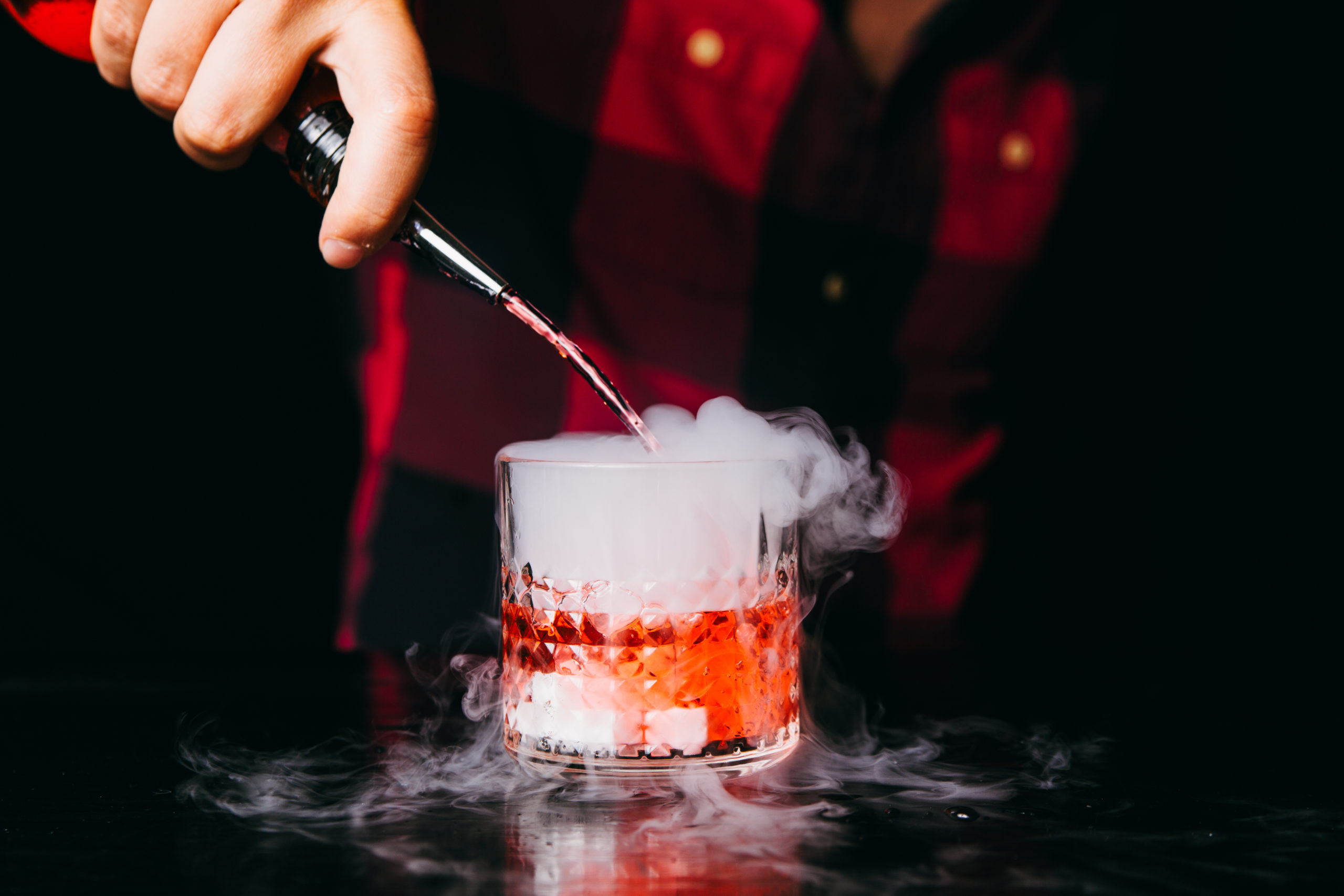 Barman making red smoking cocktail