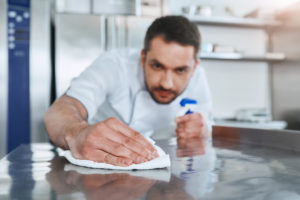 Un uomo pulisce una superficie in una cucina o in un laboratorio di produzioni alimentari