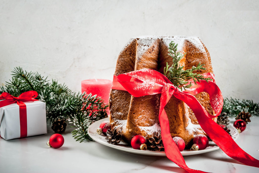 Traditional Italian Christmas fruit cake Panettone Pandoro with festive red ribbon and Christmas decorations, on white background, copy space