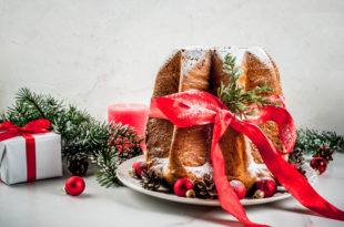 Traditional Italian Christmas fruit cake Panettone Pandoro with festive red ribbon and Christmas decorations, on white background, copy space