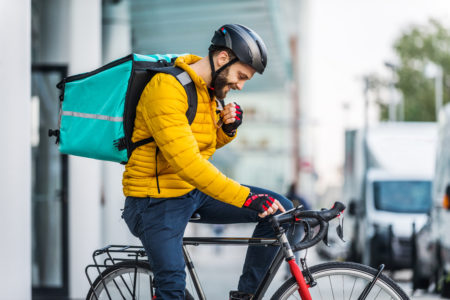 Ciclofattorino o rider per un servizio di food delivery sulla bicicletta con zaino termico in spalla