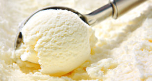 Pallina di gelato alla panna o alla vaniglia prelevata con cucchiaio apposito da una vaschetta