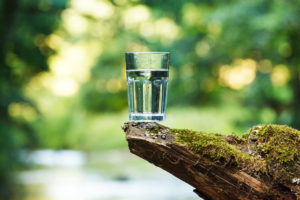 acqua, bicchiere di vetro pieno d'acqau appoggiato su una roccia