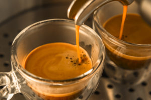 a monte di un caffè espresso forte da una macchina per caffè espresso a tazze di vetro traslucido