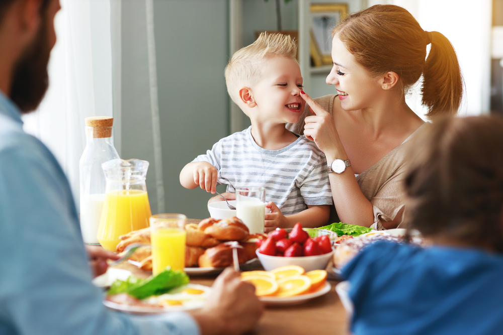 Una famiglia con bambini fa colazione a tavola; concept: genitori, madre, padre