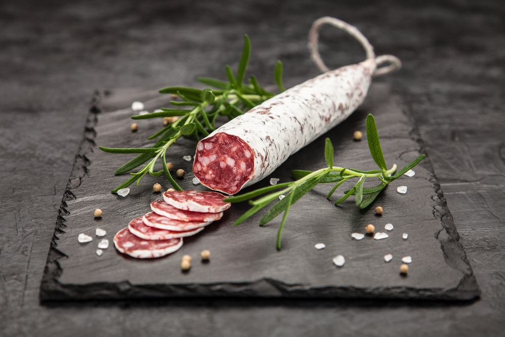 salame affettato su un tagliere di ardesia con sale e rosmarino