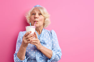 donna anziana beve frullato a base di latte con cannuccia