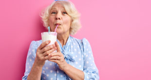 donna anziana beve frullato a base di latte con cannuccia