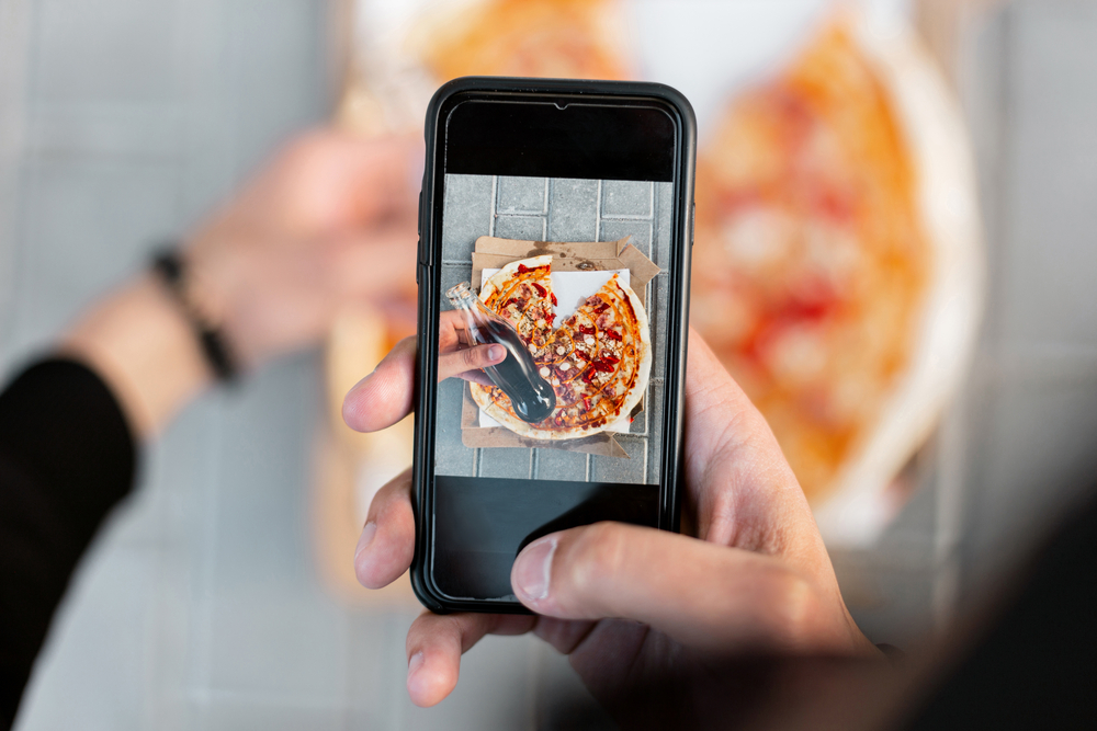post, immagine di cellulare che inquadra pizza e bibita