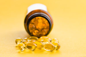 Omega 3 capsule in gel. Pillole di olio di pesce. Omega 3 salutari su sfondo giallo.
