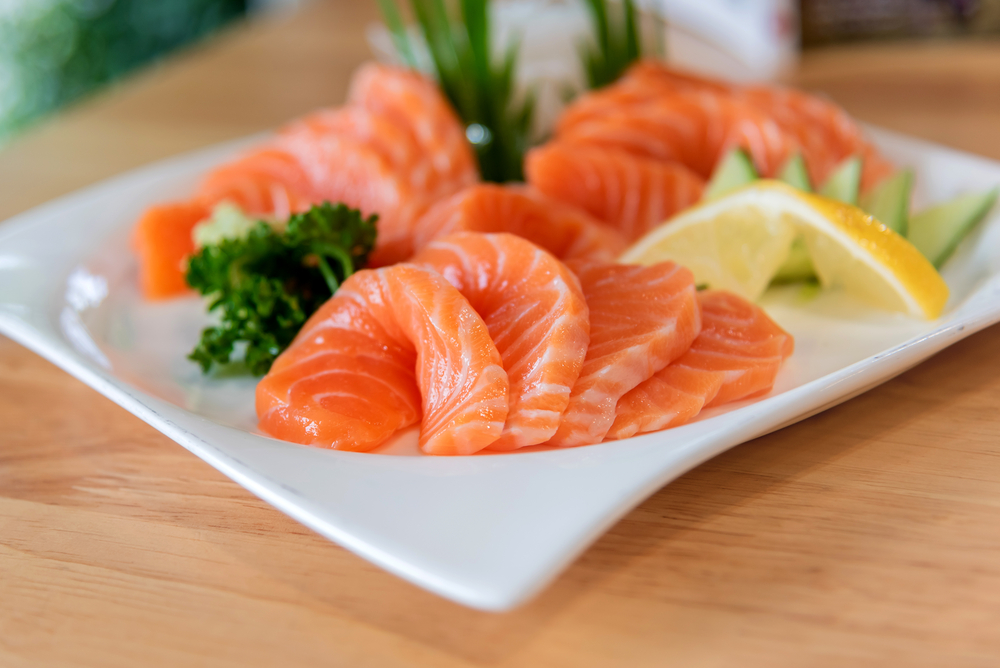 sashimi di salmone su un piatto con erbe e limone