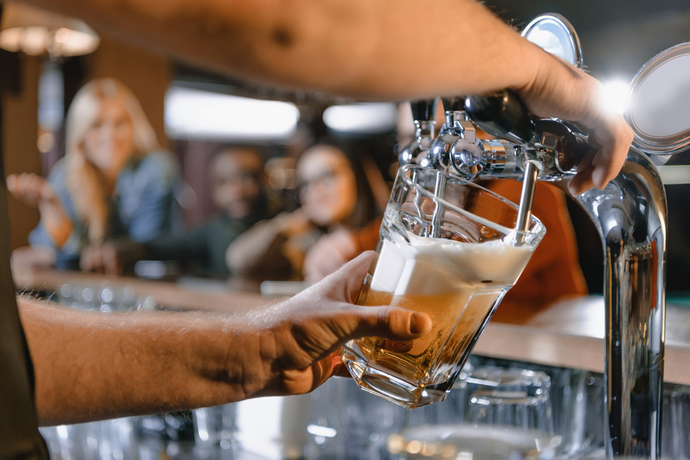 Un barista spilla un bicchiere di birra da una spillatrice in un bar o una birreria