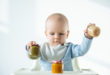 bambino che gioca con tre vasetti di omogeneizzato, baby food