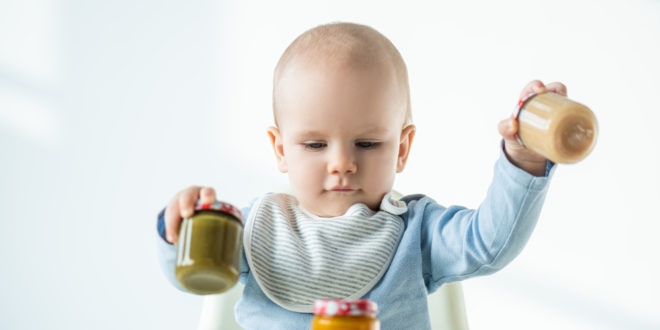 bambino che gioca con tre vasetti di omogeneizzato, baby food