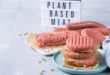 Sostituti vegetali tipo burger, salsicce e trita, con cartello sullo sfondo “plant based meat”