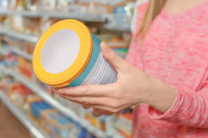 Donna esamina una confezione di latte in polvere nelle corsie di un supermercato