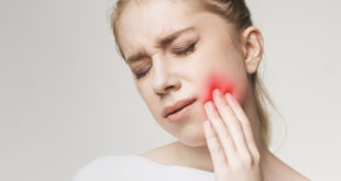 Donna che tocca la guancia dolorante, evidenziata da colore rosso; concept di mal di denti