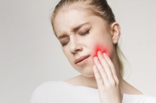Donna che tocca la guancia dolorante, evidenziata da colore rosso; concept di mal di denti