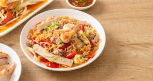 Piatto di noodles con verdure, gamberi, pollo e chili, circondato sulla sinistra da piatto con petto di pollo a fette, piatto con verdura mista e ciotolina di salsa