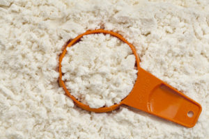 siero di latte, misurino arancione immerso nella polvere di siero di latte