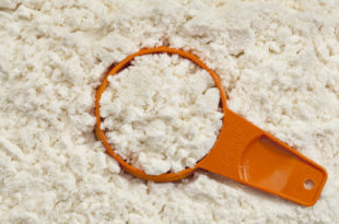siero di latte, misurino arancione immerso nella polvere di siero di latte
