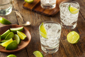 Due bicchieri di gin tonic, con ghiaccio e lime, accanto a un piattino di fette di lime; Concept: alcol, alcolici