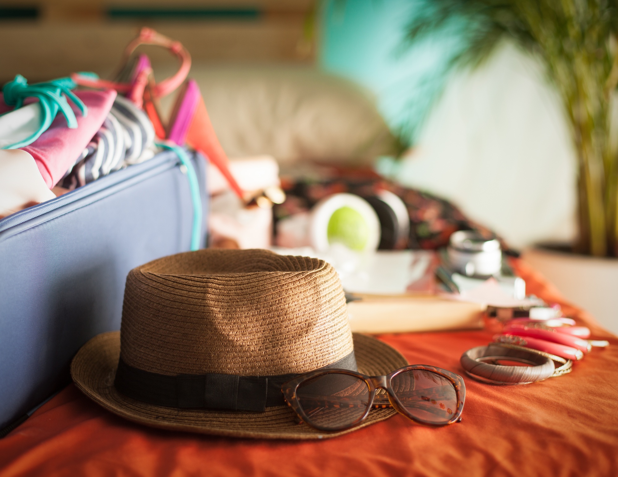 Cappello di paglia, occhiali da sole, angolo di valigia su letto, concept: Viaggio, tossinfezioni