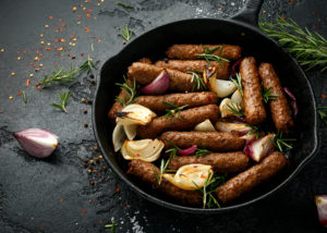 Salsicce vegane vegetariane al rosmarino e cipolla cotte al forno in padella di ghisa.