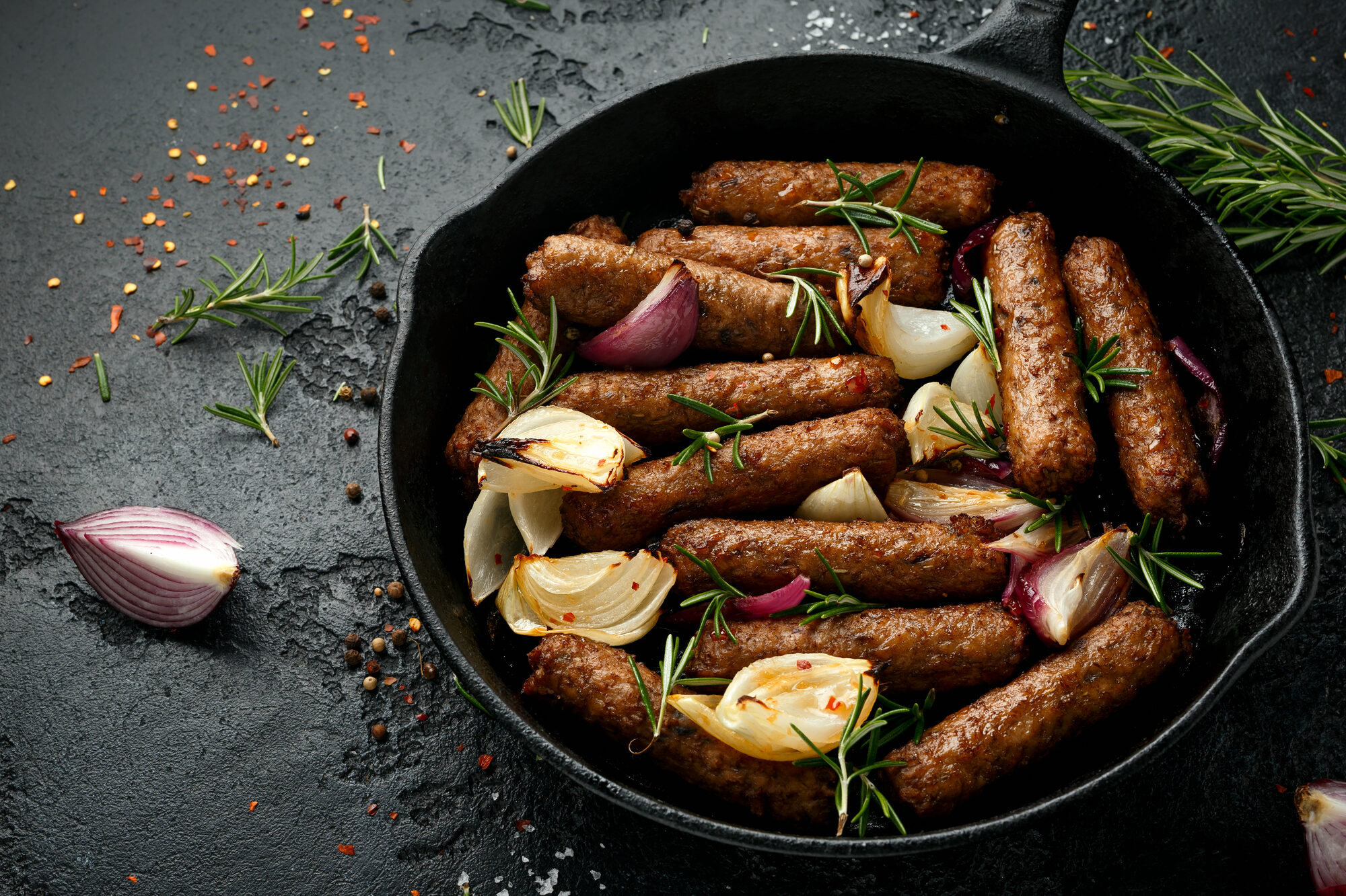 Salsicce vegane vegetariane al rosmarino e cipolla cotte al forno in padella di ghisa.