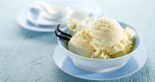 Coppetta di gelato alla vaniglia con bacche di vaniglia, appoggiata su un piattino