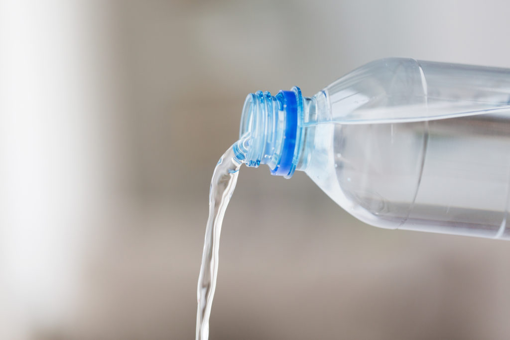 acqua versata da bottiglia di plastica trasparente microplastiche