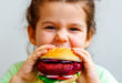 Bambina mangia panino con burger vegetale