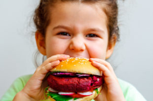 Bambina mangia panino con burger vegetale