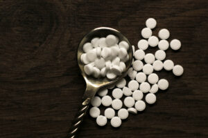 concetto diabete. Sostituto dello zucchero, dolcificante in confetti in cucchiaio su sfondo di legno scuro, dolcificanti