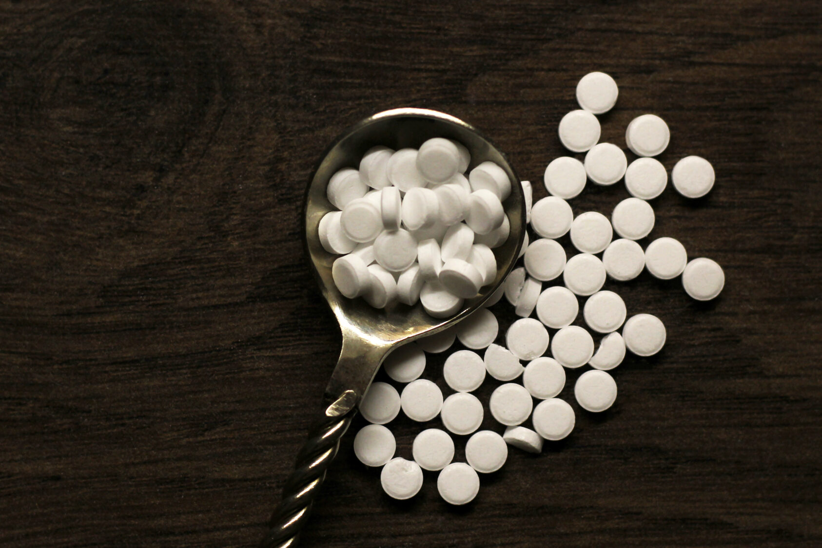 concetto diabete. Sostituto dello zucchero, dolcificante in confetti in cucchiaio su sfondo di legno scuro, dolcificanti