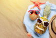 Concept buone vacanze: cocco e ananas su asciugamano in spiaggia con occhiali da sole