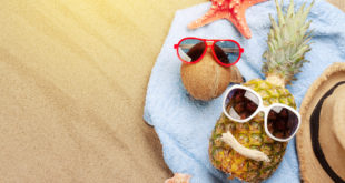Concept buone vacanze: cocco e ananas su asciugamano in spiaggia con occhiali da sole