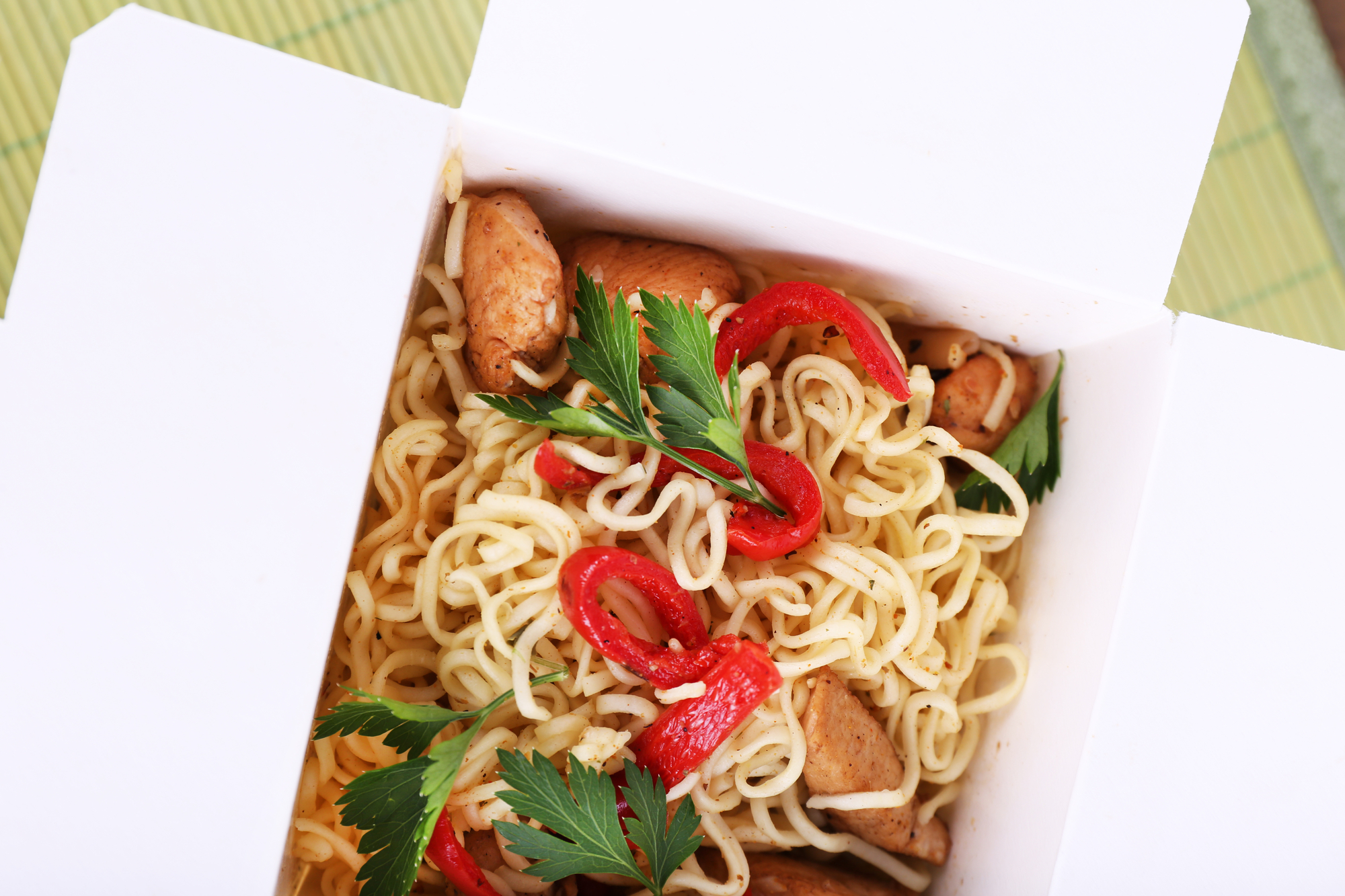 Noodles con verdure e carne in un contenitore di carta per cibo da asporto